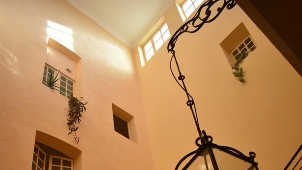 Una scala con ringhiere nere decorate e un lampadario a sospensione.