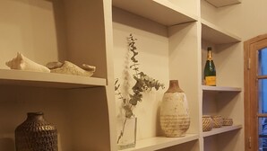 Un corridoio con scaffali bianchi che espongono diversi oggetti decorativi, tra cui vasi, una candela e un libro.