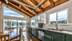 A modern kitchen with a dishwasher, a coffee maker, and a sink. There is a dining area with a table and chairs.