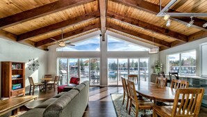 A spacious living area with a high ceiling, wooden beams, a large dining table, and a cozy seating arrangement.