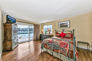 Un dormitorio con una cama grande, vistas a un lago y una puerta corrediza de vidrio que da a un espacio exterior.