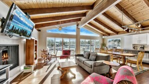 A spacious living area with a fireplace, a large sofa, a dining table, and a kitchen area.