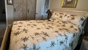 A bedroom with a bed, a ceiling fan, a nightstand, a lamp, a framed picture, and a wardrobe. - Beach Vacation Condo (Myrtle Beach)