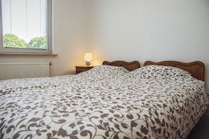 Una camera da letto con un letto, un comodino con una lampada e una finestra con persiane.