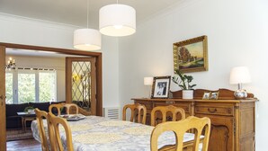 A dining area with a wooden table and chairs, a chandelier, and a painting on the wall. - Lovely spacious house close to parks and tramway (Antwerpen)