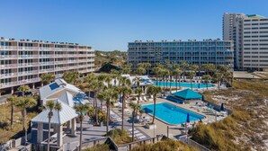 Een resort met verschillende zwembaden, palmbomen en moderne gebouwen.