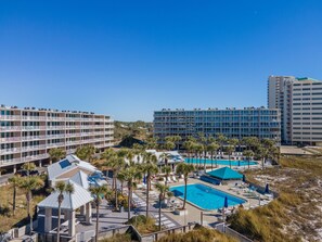 Ein Resort mit mehreren Schwimmbecken, Palmen und modernen Gebäuden.