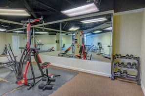 Un gimnasio con equipo de ejercicio, un espejo y un estante con mancuernas.