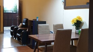 Ein Essbereich mit Holztisch und -stühlen, einer schwarzen Deckenleuchte und einer Vase mit gelben Blumen.