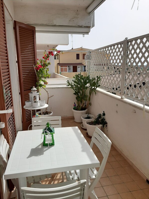 A balcony with a white table and chairs, potted plants, and a white lattice fence. - Miguel Apartment located in the center of Tropea, a stone's throw from the sea (Tropea)