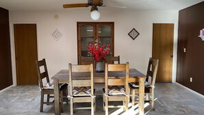 A dining area with a wooden table and chairs, a ceiling fan, and a vase with red flowers. - Charming home in Country Club Estates (Sierra Vista)
