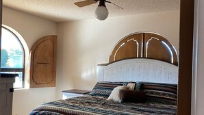 A bedroom with a bed, a ceiling fan, a wooden headboard, and a window. - Charming home in Country Club Estates (Sierra Vista)