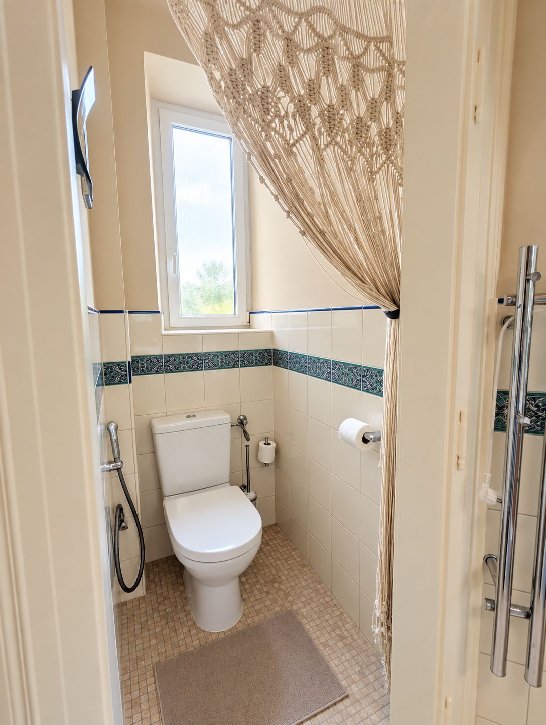 A small bathroom with a toilet, a shower, and a window.