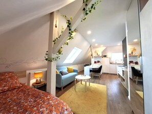 A modern loft apartment with a loft bed, a sofa, a dining table, and a kitchen area. - Le Jardin des Roses (Saverne)