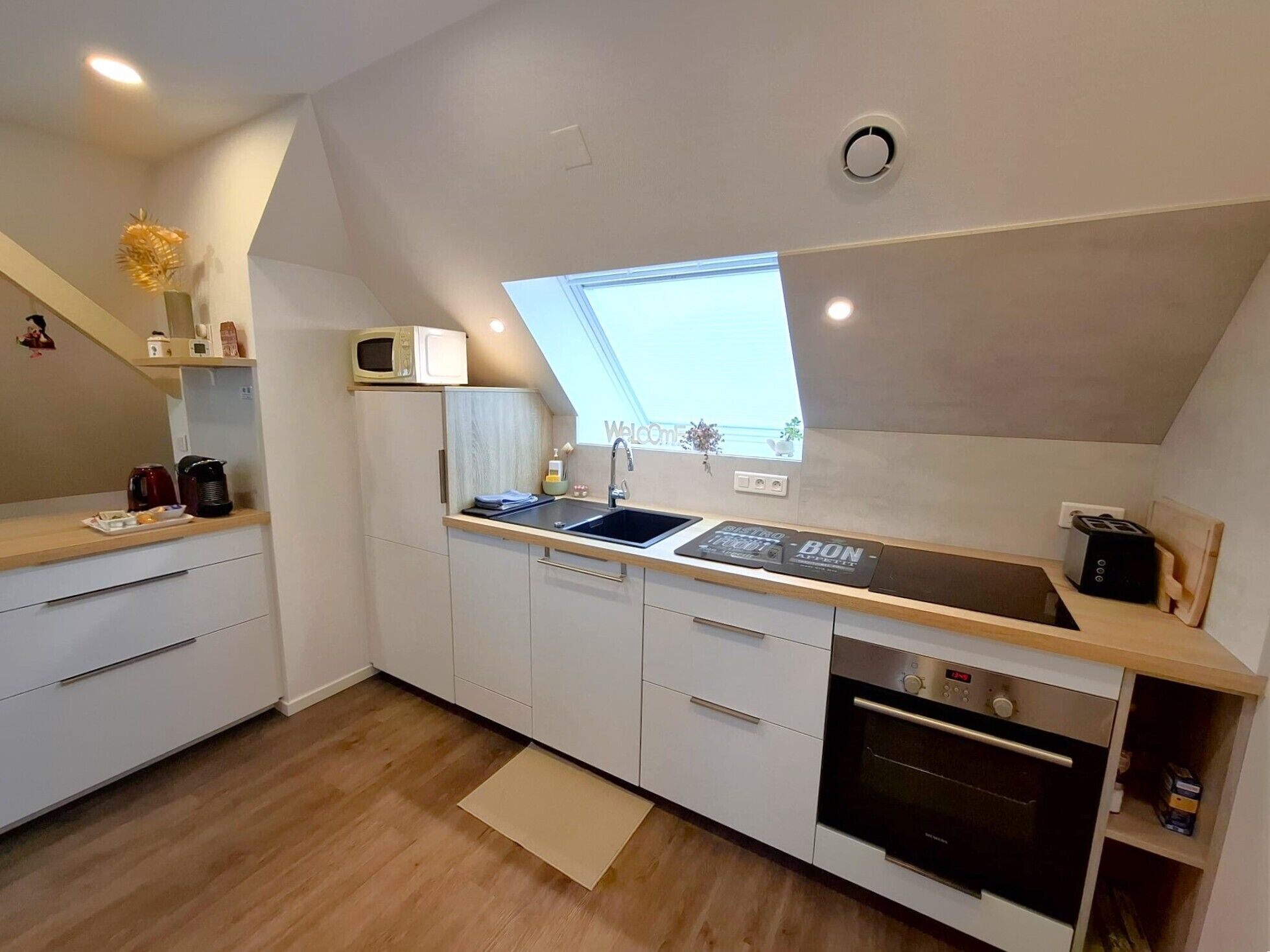 A compact kitchen with a built-in microwave, a sink, and a toaster.