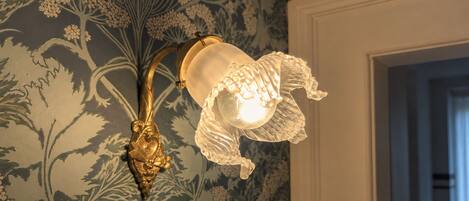 A wall-mounted light fixture with a floral design and a decorative gold-colored base.