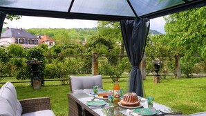 Una terrazza esterna con mobili in vimini, un tavolo in vetro e una torta.