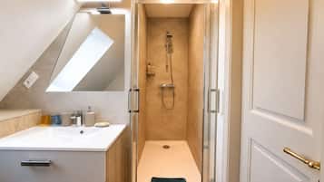 A modern bathroom with a shower, a sink, and a mirror.