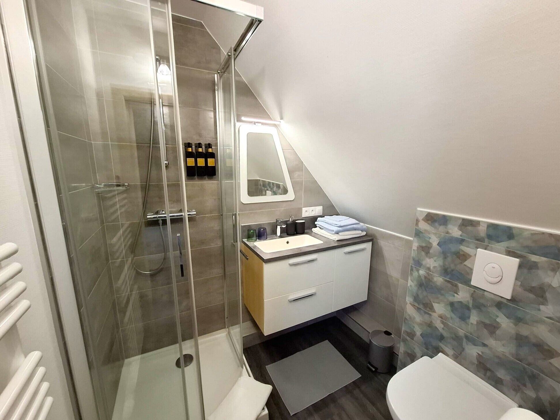 A modern bathroom with a glass-enclosed shower, a white sink, and a mirror above it.