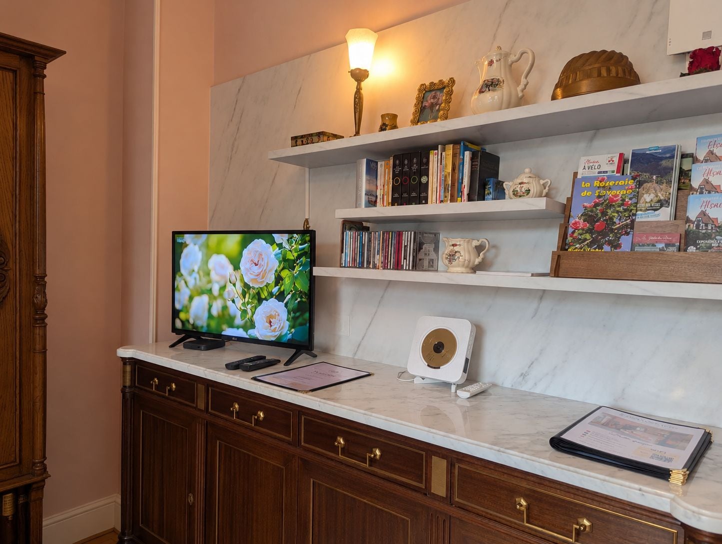 Une pièce avec un téléviseur posé sur un comptoir en marbre, des meubles en bois et des étagères remplies de livres et d’objets décoratifs.