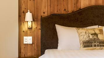 A bedroom with a wooden headboard, a bedside lamp, a nightstand with drawers, and a bed with white bedding.
