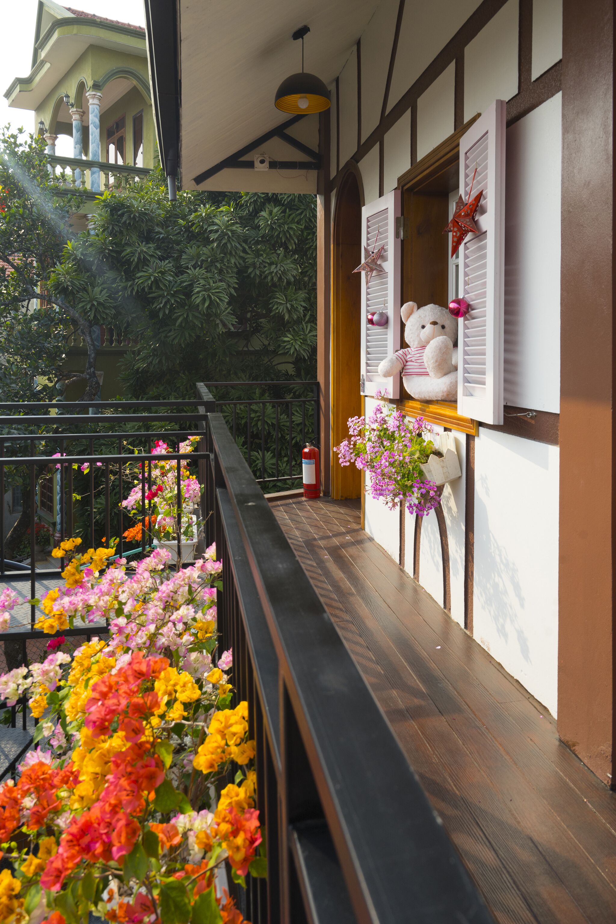 A balcony with wooden flooring, a railing, and a view of a building with columns.