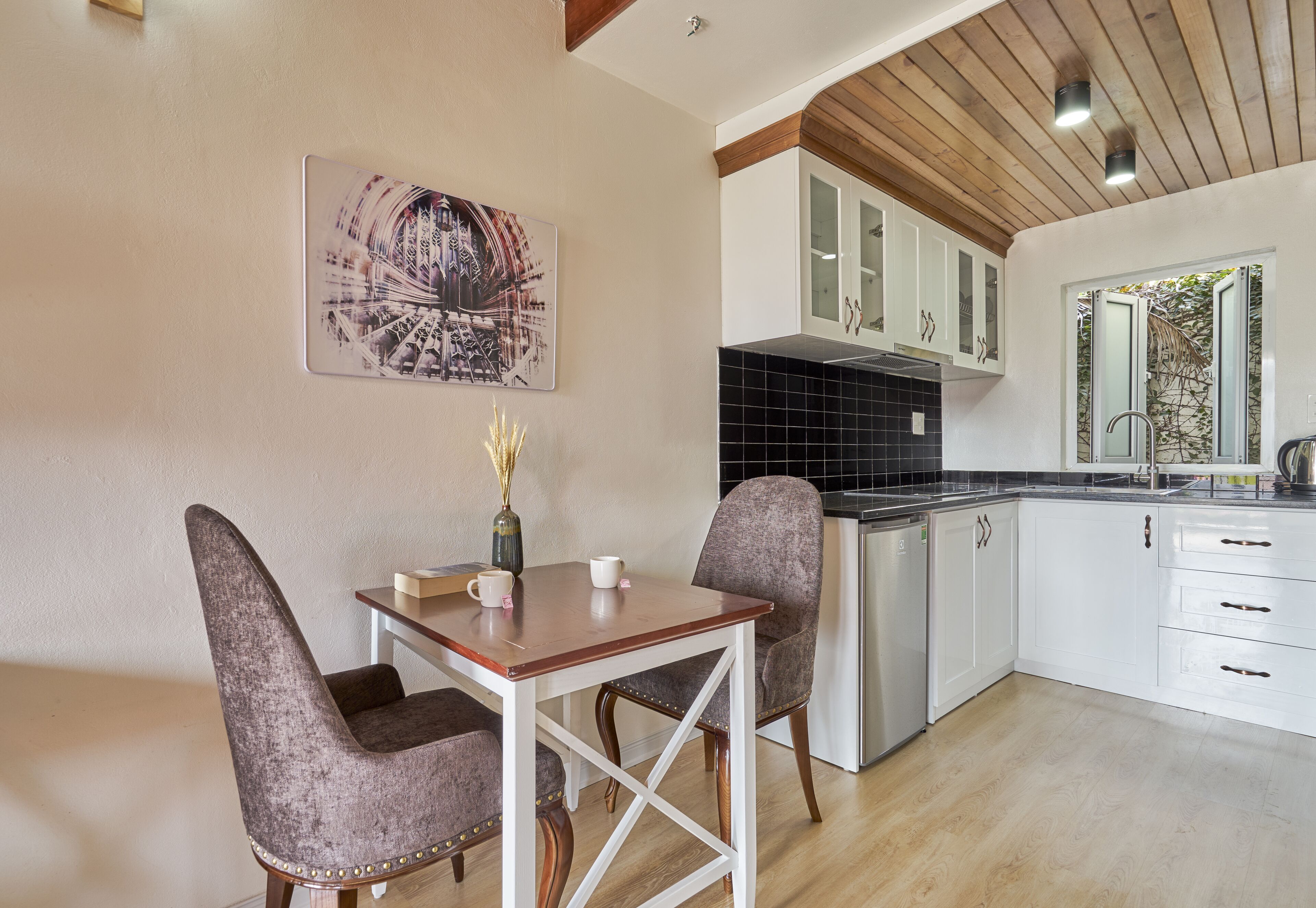 A modern kitchen with white cabinets, a black tiled backsplash, and a wooden ceiling.