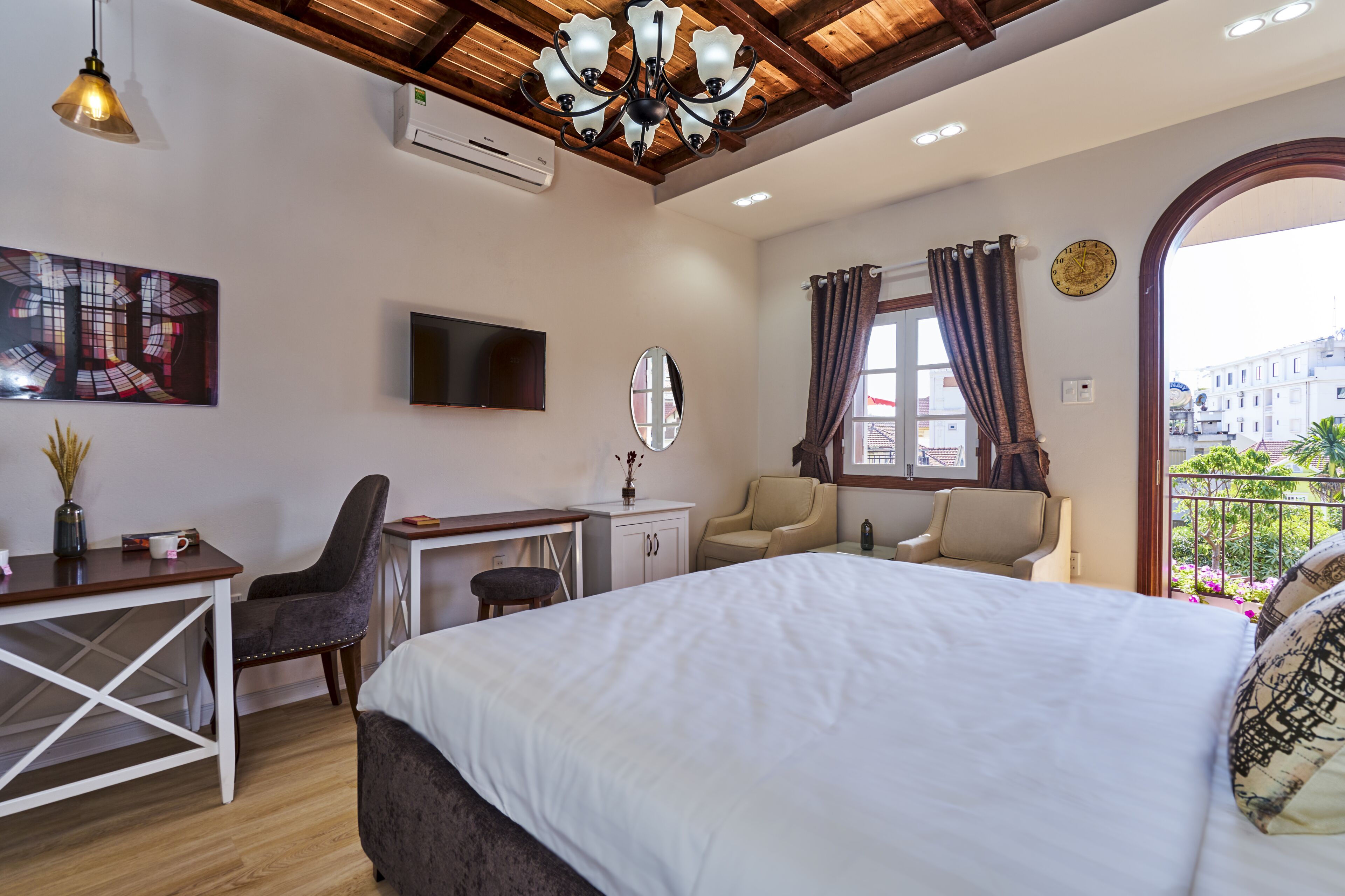 Habitación de hotel con cama, escritorio, silla, televisión y vista a la ciudad por la ventana.