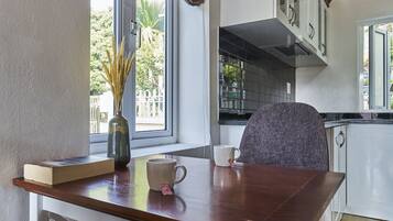 Eine Küche mit einem Holztisch, einer Vase mit Trockenblumen, einem Buch und einer Tasse.
