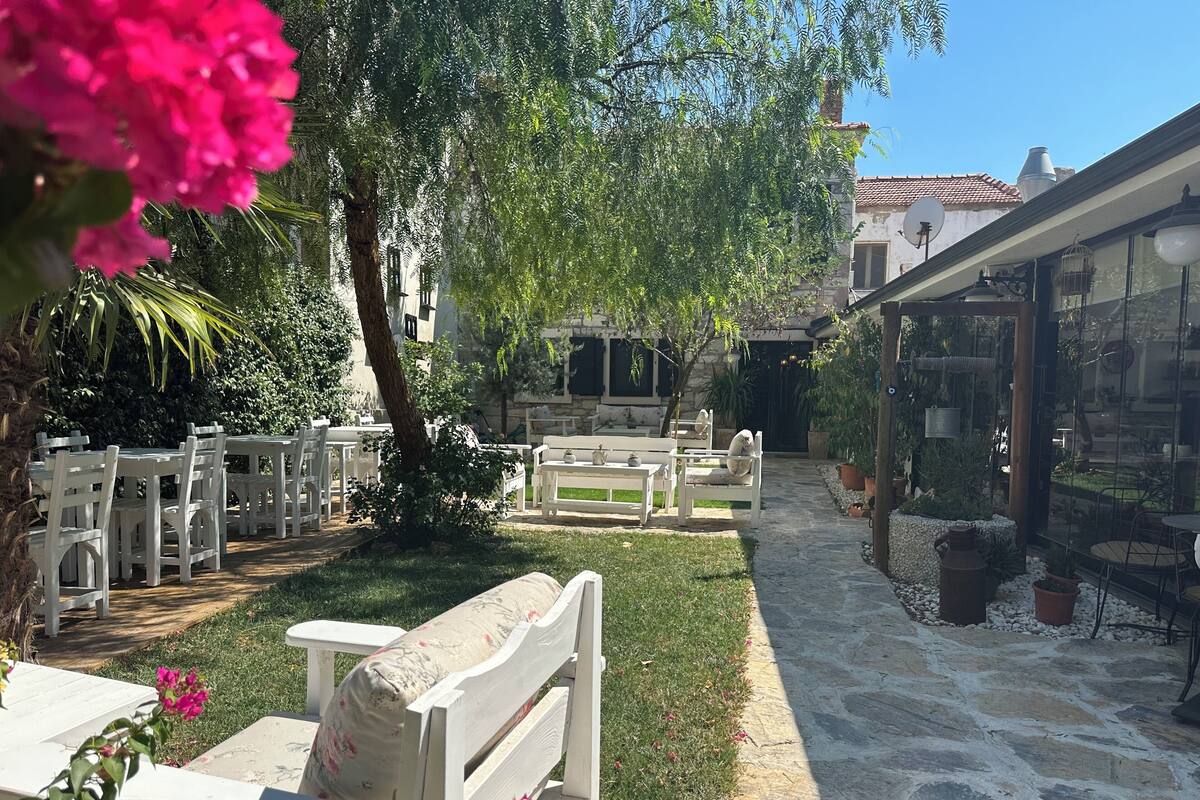 An outdoor seating area with white wooden furniture, a stone pathway, and potted plants.