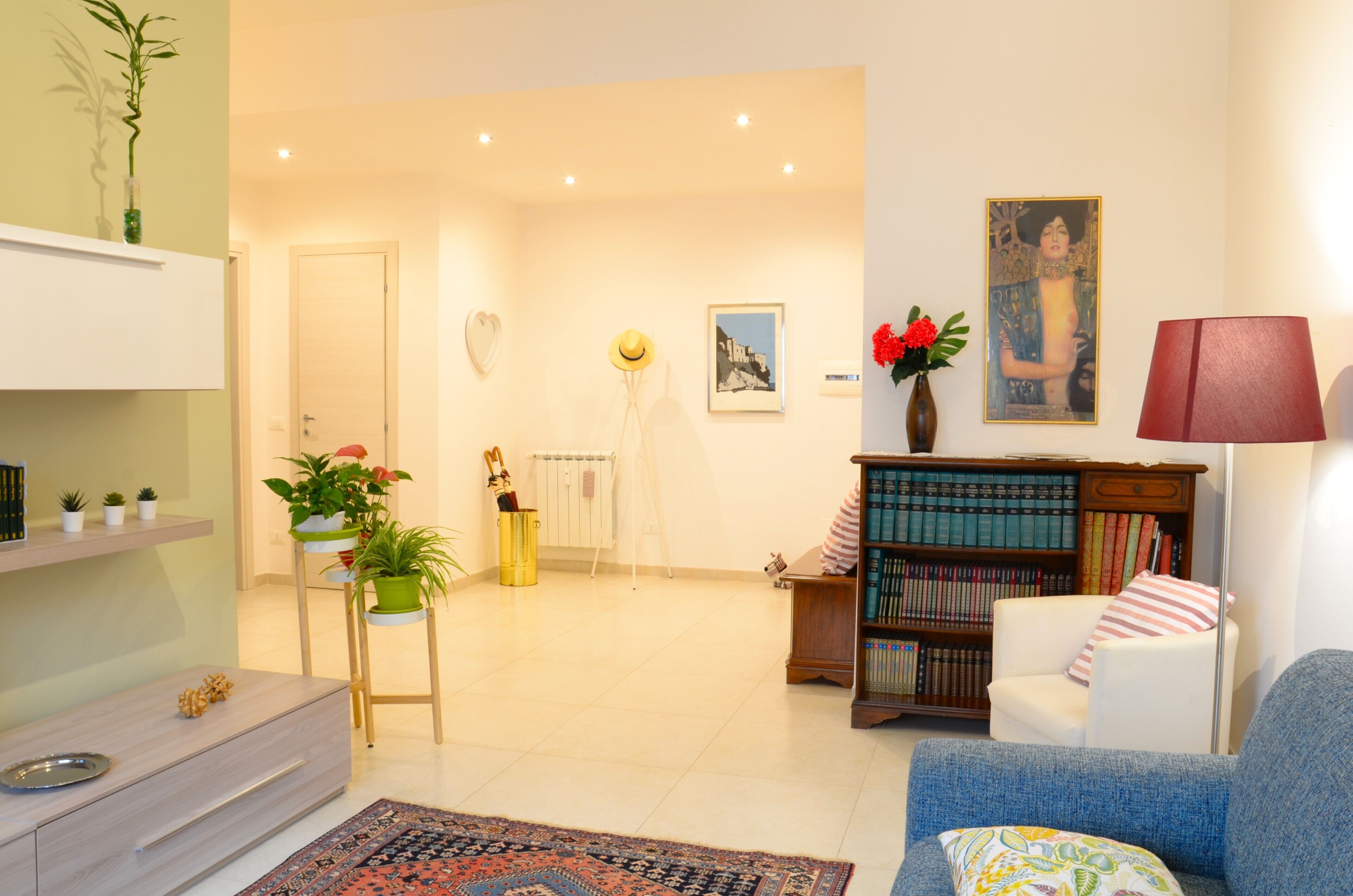 A living room with a bookshelf, a sofa, a dining area with a table and chairs, and a radiator. - Egle's House (Roma)