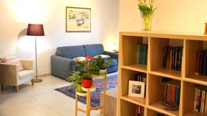 A living room with a sofa, a small table with plants, a bookshelf, and a lamp. - Egle's House (Roma)
