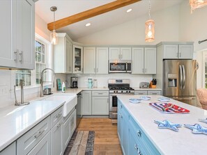 Enjoy cooking in this well-equipped kitchen with a large island, stainless steel appliances, and pendant lighting.