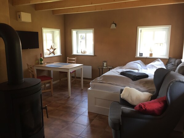Um quarto aconchegante com uma cama, um sofá, uma mesa e uma lareira.