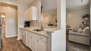 A modern kitchen with white cabinets, a double sink, and a coffee maker. - High Tech Hideaway: The modern beach lifestyle (Rehoboth Beach)