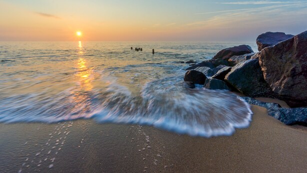 A beach with rocks and waves at sunset. - High Tech Hideaway: The modern beach lifestyle (Rehoboth Beach)
