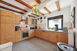 A kitchen with wooden cabinets, a stove, a sink, and a window with a view.