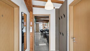 Un pasillo con puertas de madera, una lámpara en el techo y vista a una habitación con un sofá y una mesa.