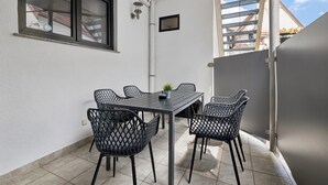 Un patio con una mesa, sillas, una ventana y una puerta.