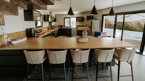 A modern kitchen with a large island, pendant lighting, and a view of the outdoors.