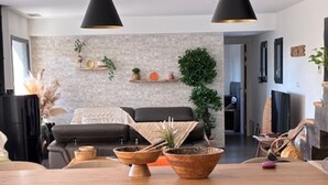 A modern dining area with a wooden table, black chairs, and pendant lighting.