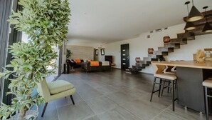 A spacious living area with a modern kitchen, a staircase, and a seating area with a sofa and chairs.