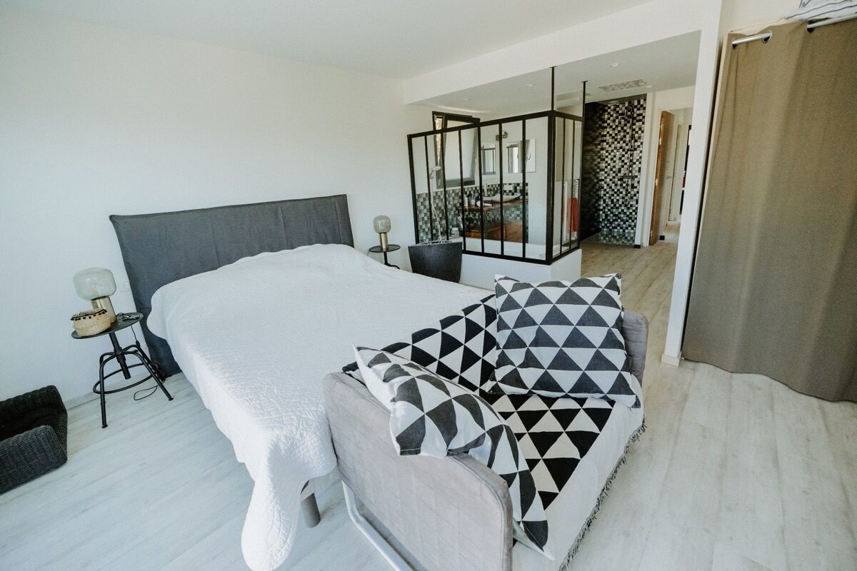 Een moderne slaapkamer met een groot bed, een nachtkastje en een spiegel.