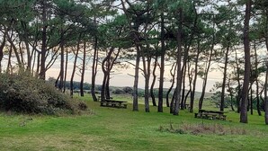 A grassy area with several picnic tables and trees. - House with enclosed garden, on the sea side (Brem-sur-Mer)