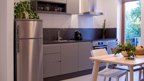 Eine moderne Küche mit Edelstahlgeräten, grauen Schränken und einem Essbereich mit weißem Tisch und Stühlen.