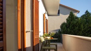 Ein Balkon mit Tisch, Stühlen und einem Blumentopf.