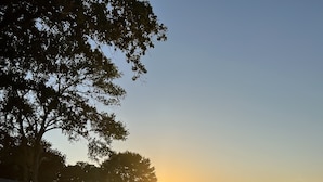 Une jetée en bois s’étendant au-dessus d’une étendue d’eau calme, au coucher du soleil.