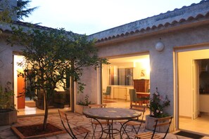 An outdoor patio with a round table and chairs, surrounded by potted plants and a small tree. - Sunlit villa, 2 min walk to Valbonne village (Valbonne)