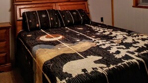 A bedroom with a wooden headboard, a patterned bedspread, and a ceiling fan.