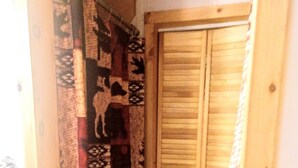 A narrow hallway with a wooden door and a patterned curtain.